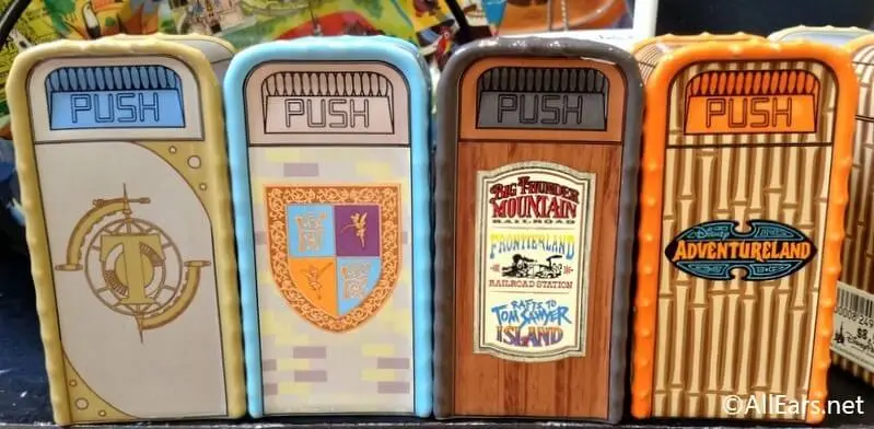Close-up photo of four Disney theme park trash can replicas from Tomorrowland, Fantasyland, Frontierland, and Adventureland, highlighting Disney’s iconic themed design details.